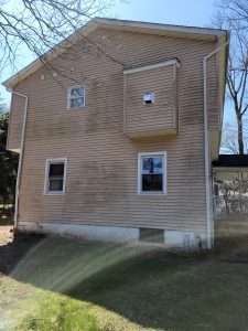 Photo of vinyl siding of house with mildew and algae before a whole house wash by Hydro Eco Clean