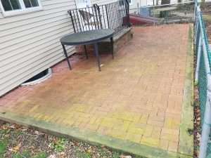 Patio table and brick hardscape features covered in organic growth before pressure washing with Hydro Eco Clean