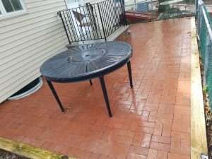 Patio table and brick hardscape features covered in organic growth after pressure washing with Hydro Eco Clean