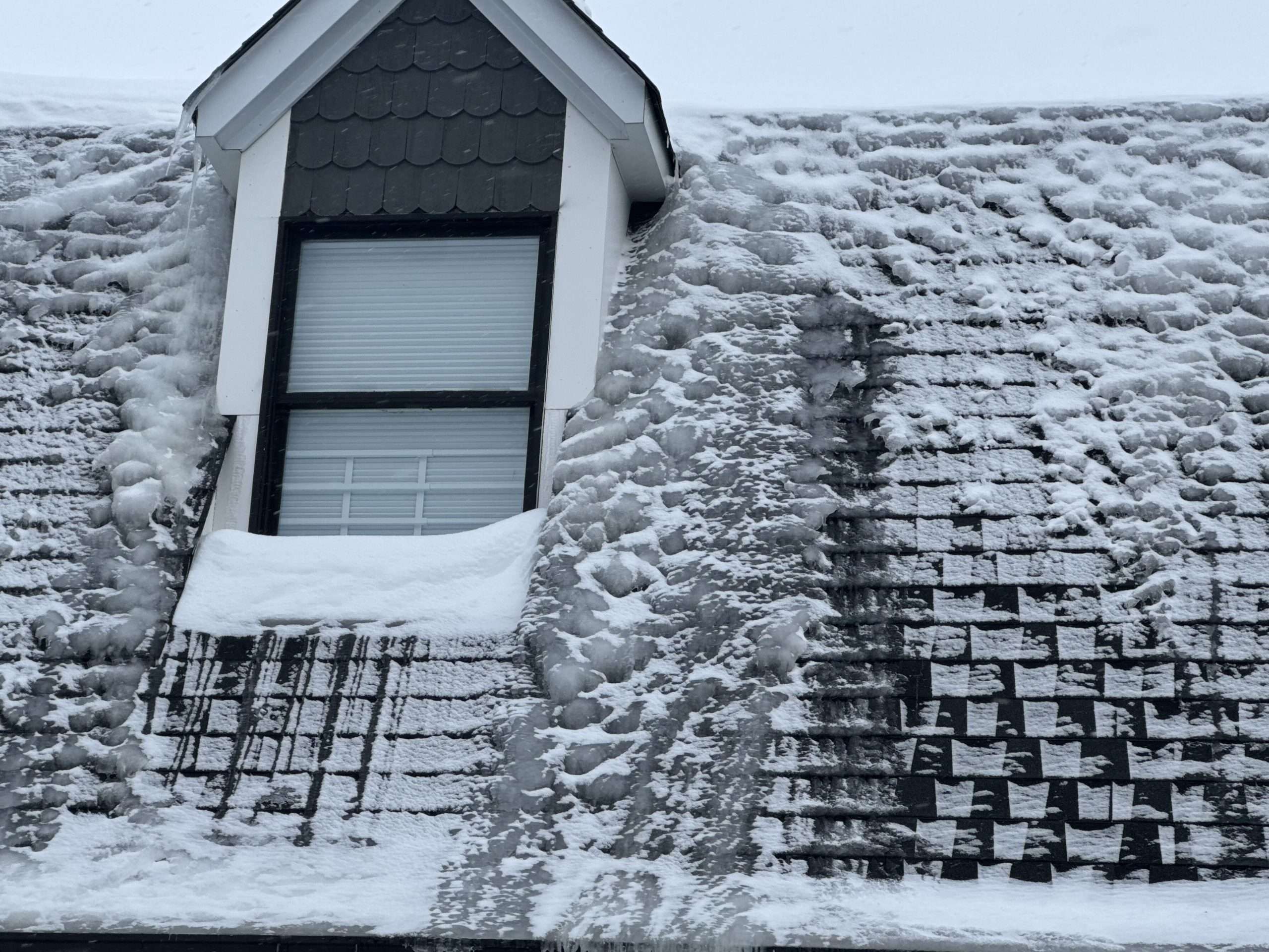 Snow and ice accumulation across a residential roof during winter