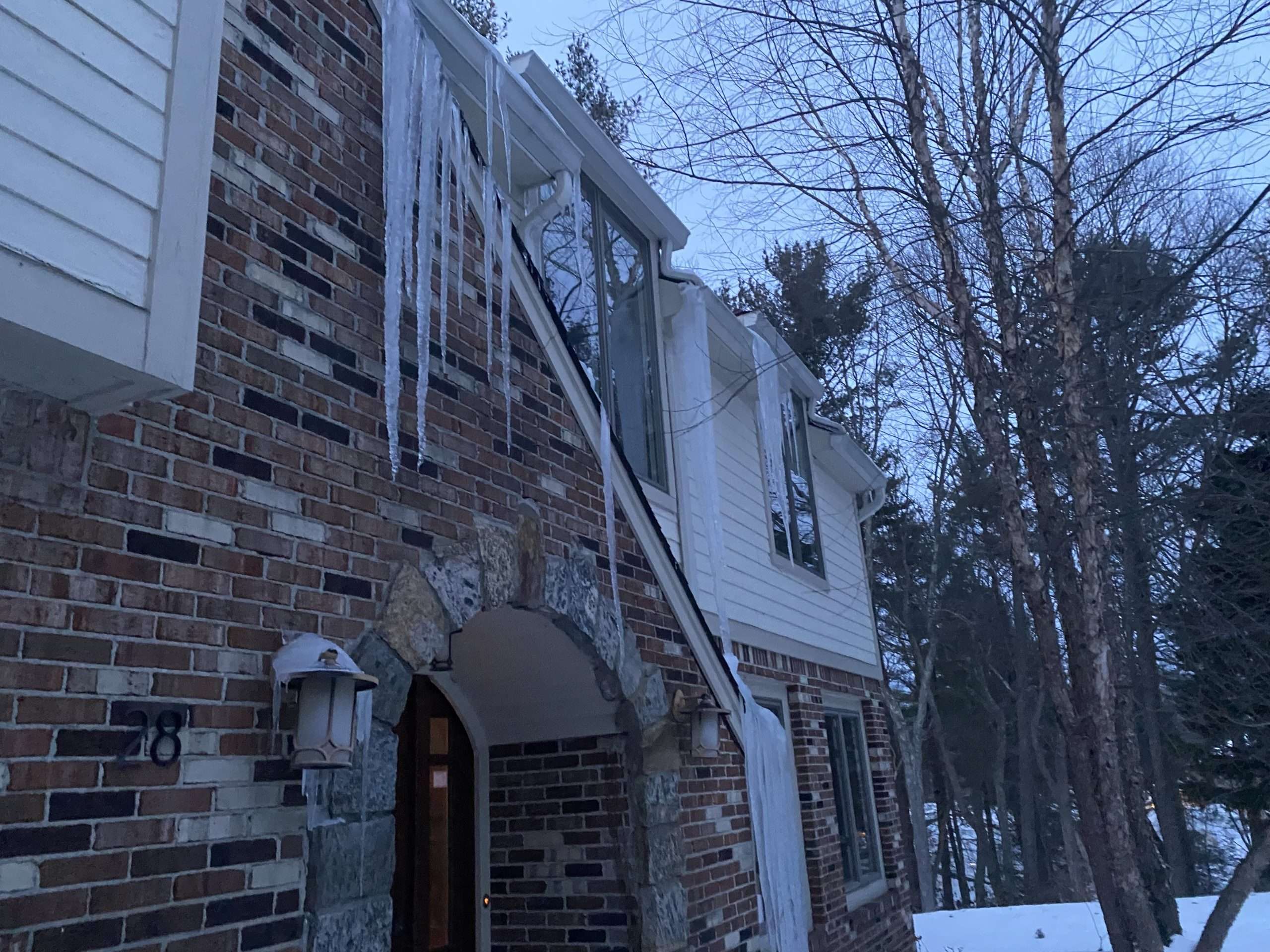 Large icicles and ice buildup hanging from the roofline of a New Jersey home